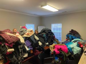 Volunteers behind pile of coats