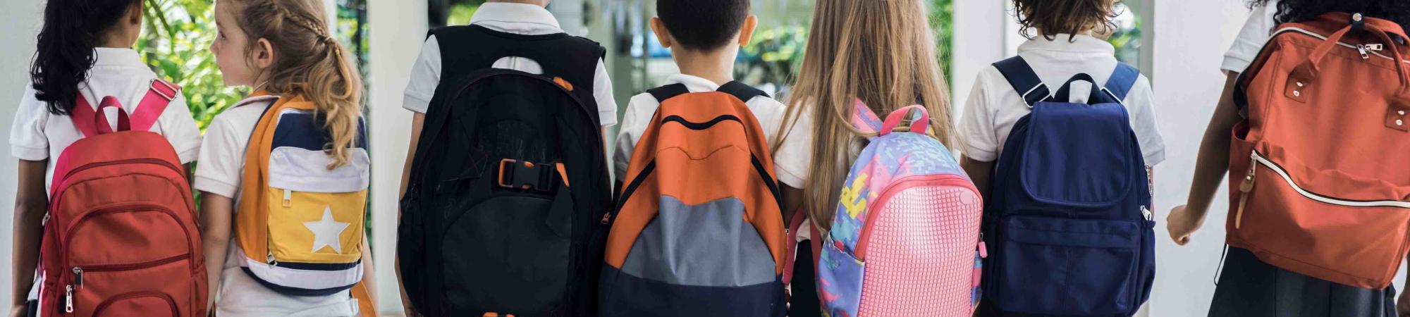 young kids with their backs turned wearing backpacks