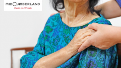 seated elderly woman holding the hand of someone standing behind her