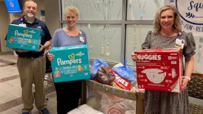 volunteers holding items from diaper drive